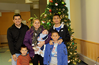 Una familia sonriente junto a un árbol de Navidad